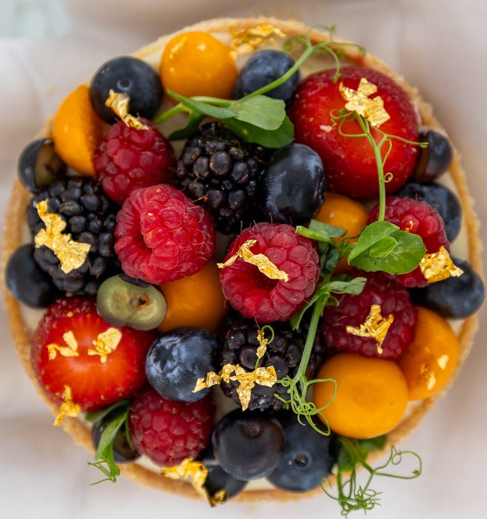 A vibrant fruit tart adorned with berries and edible gold, captured in Bodrum, Türkiye.