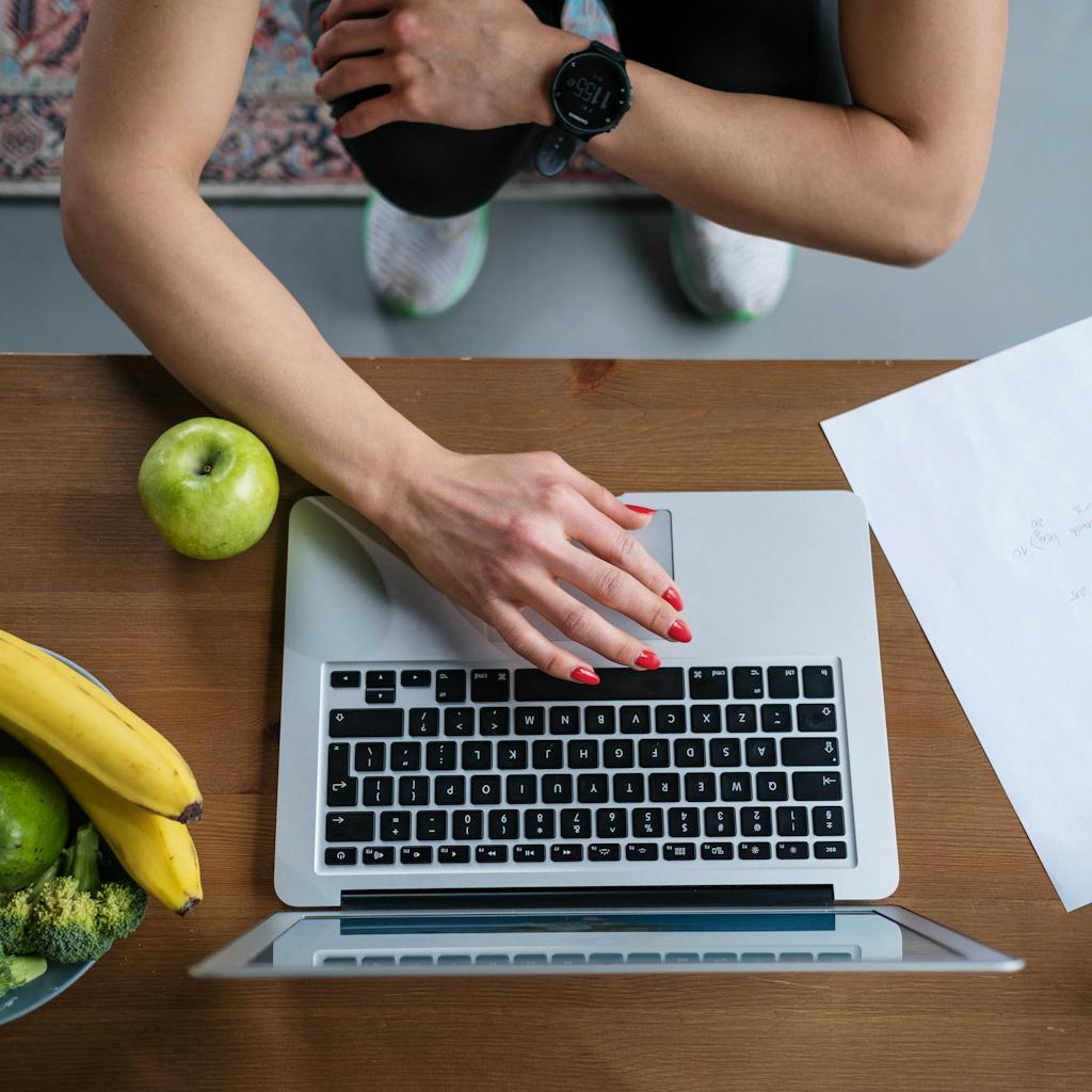 zdjęcie autorstwa ron lach Overhead view of hands on laptop with fruits, vegetables, and paper on wooden table.