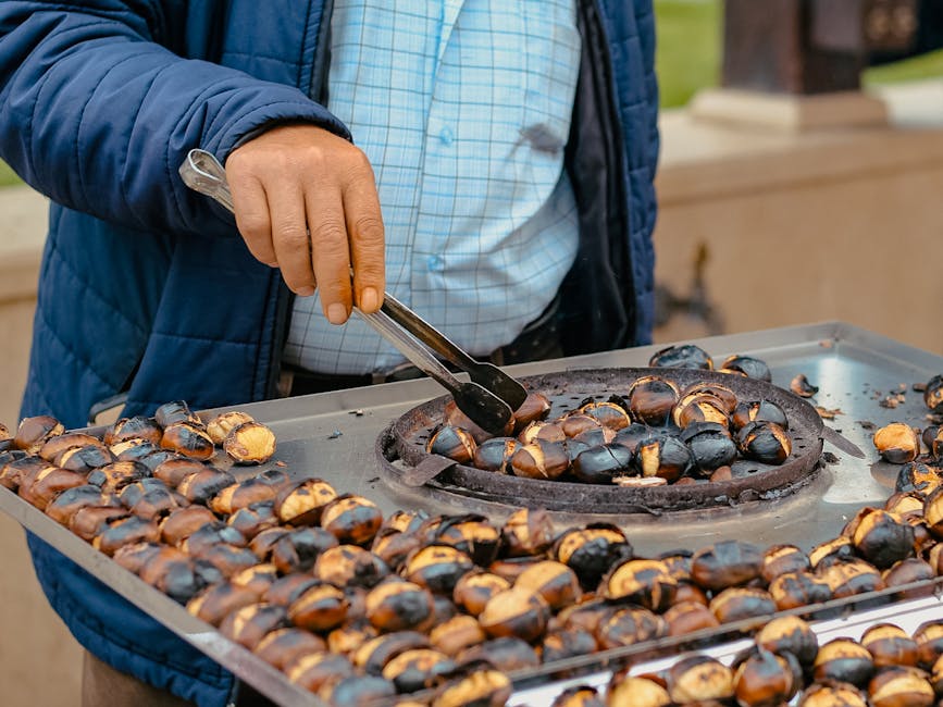 Close-up of a man cooking roasted chestnuts on the street, showcasing traditional outdoor food preparation.