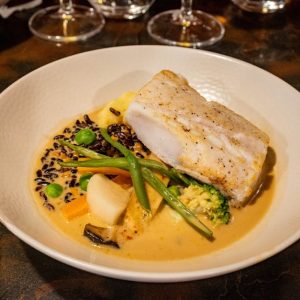 A delicious gourmet seafood dish featuring cod, vegetables, and creamy sauce.