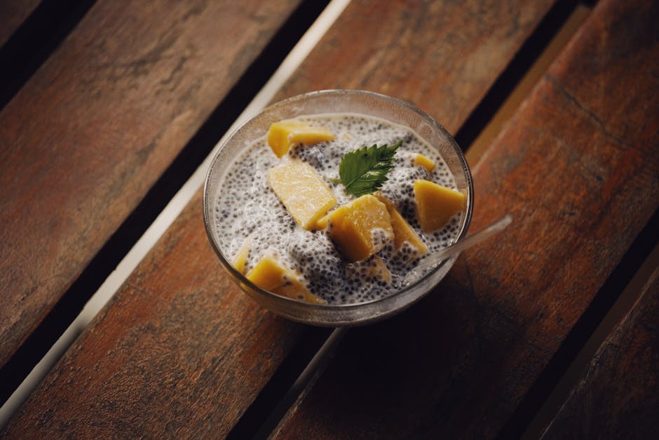 Creamy chia seed pudding topped with fresh mango cubes and a parsley leaf, perfect for a healthy snack.