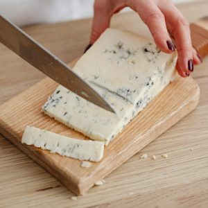Ser gorgonzola krojony na nożem na drewnianej desce