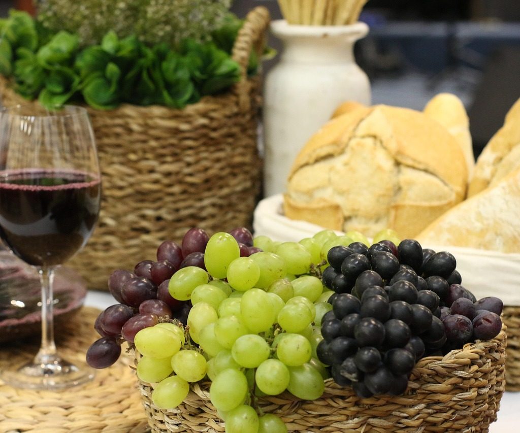 Świeże winogrona w odmianie czarnej i zielonej podane ze świeżym pieczywem oraz lampką wytrawnego trunku