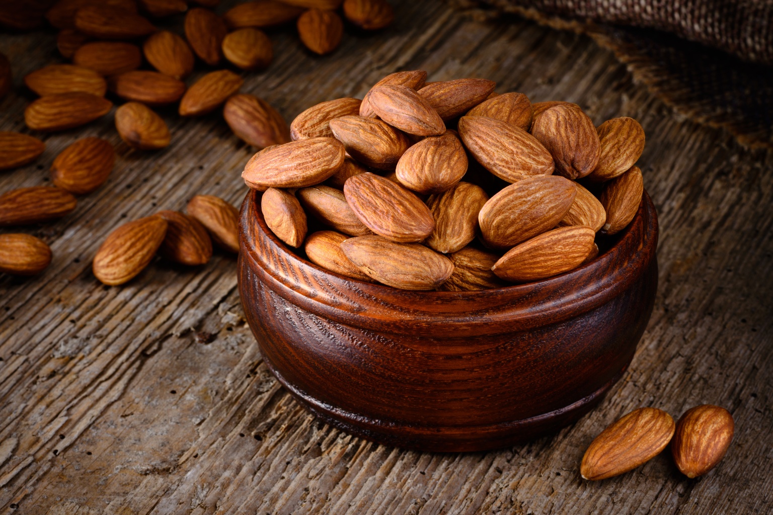 Porcja migdałów w drewnianej misce, na starym drewnianym blacie