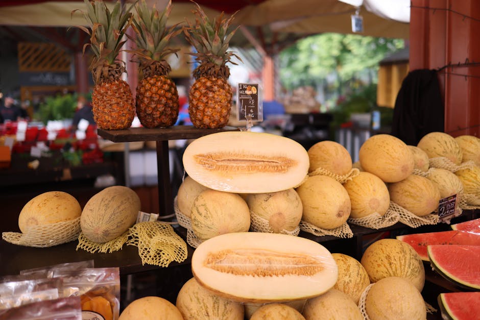 Żywa ekspozycja świeżych melonów i ananasów na straganie na świeżym powietrzu.