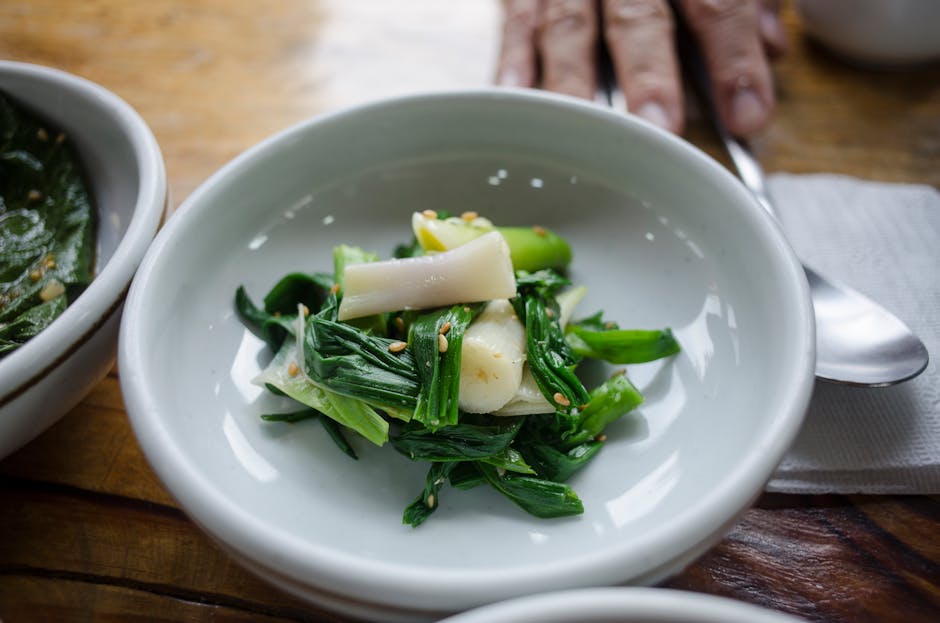 Zbliżenie świeżego dodatku z pora i zielonych warzyw, podanego w białym spodku, udekorowanego nasionami sezamu.