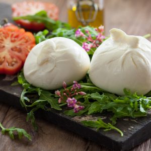 Burrata na desce degustacyjnej z ziołami i pomidorem.