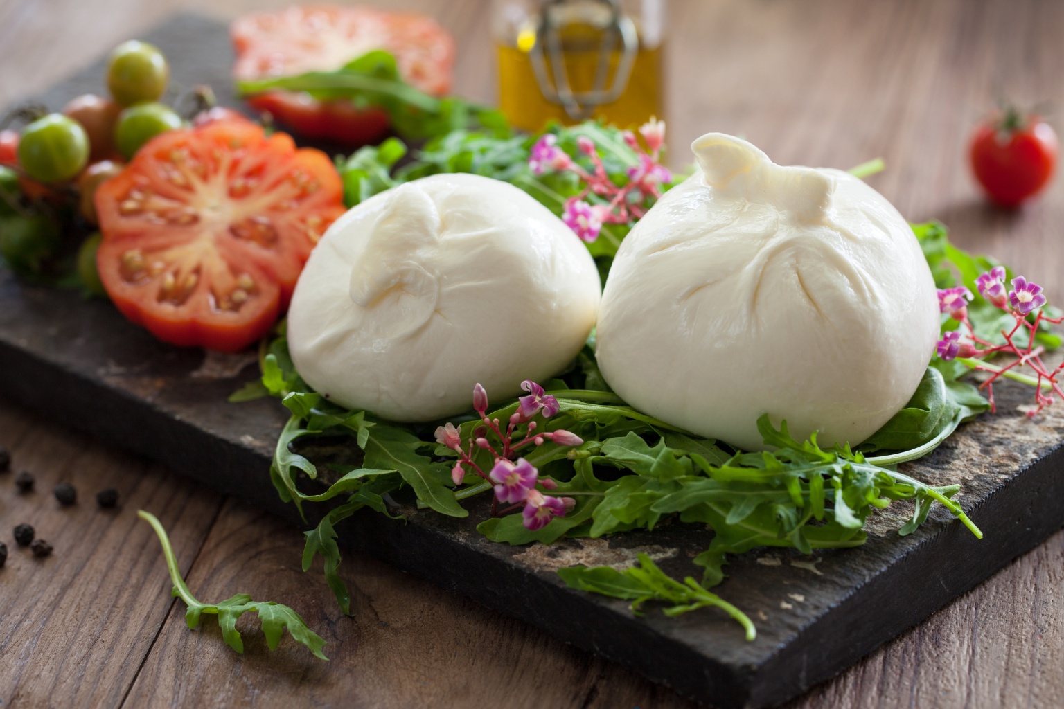 Burrata na desce degustacyjnej z ziołami i pomidorem.