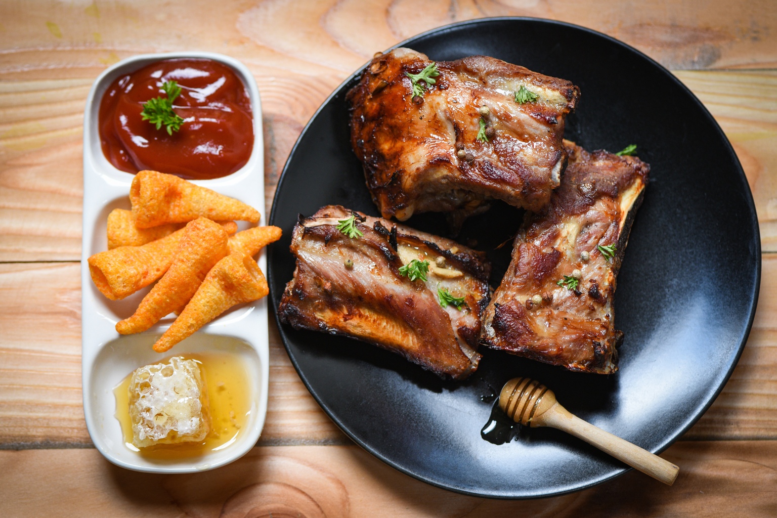 Pieczone żeberka w glazurze miodowej z sosem barbecue, kawałkiem plastra miodu i chrupiącą przekąską kukurydzianą na drewnianym stole.