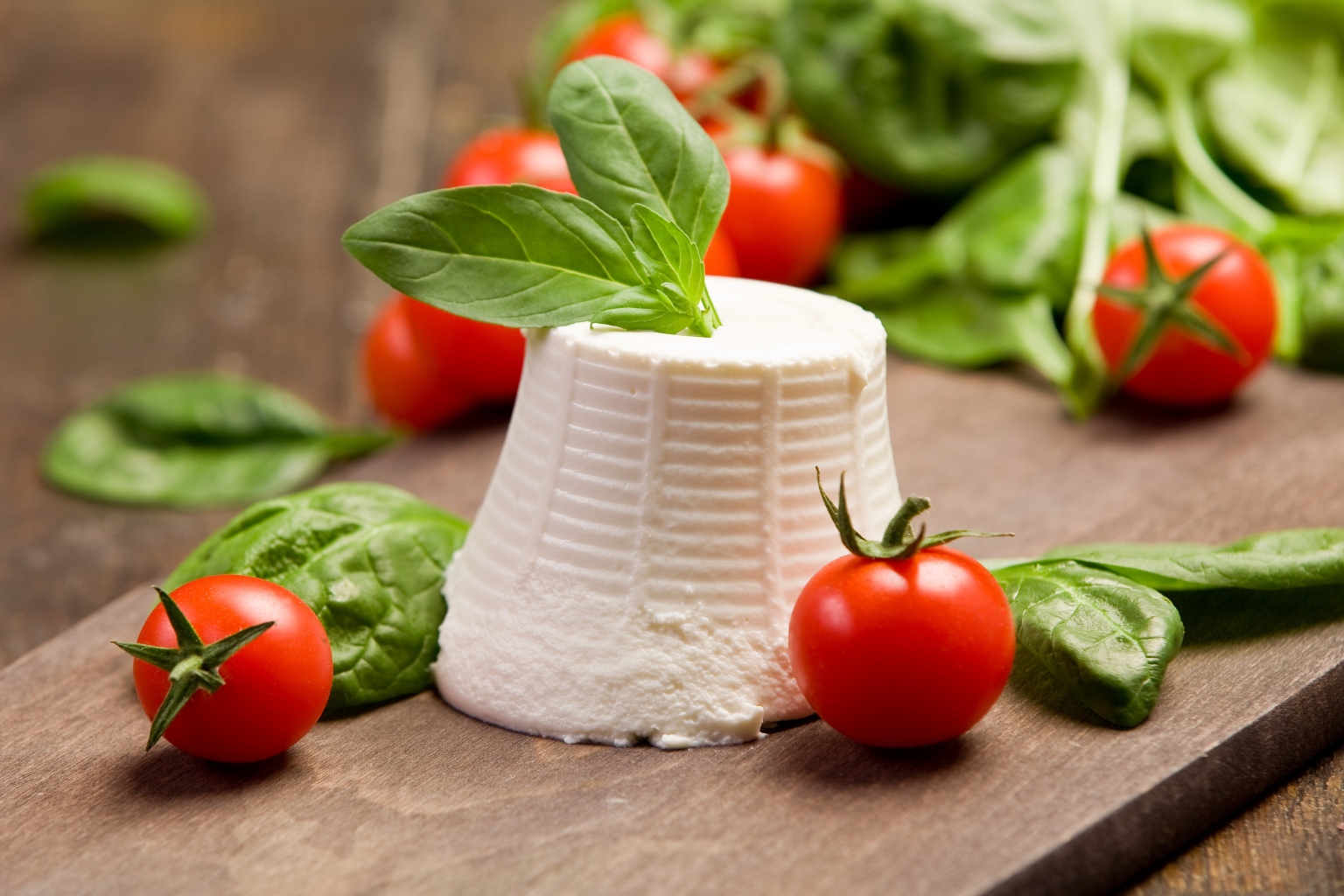 ricotta z pomidorami i bazylią na drewnianym stole