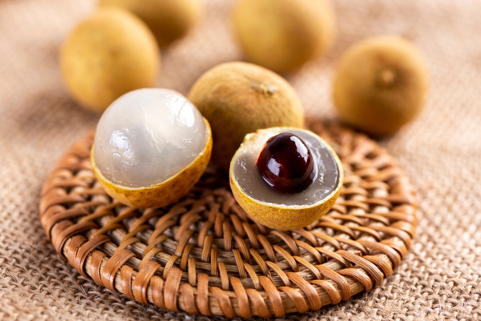 longan w przekroju pod grubą skórką posiada biały miąższ oraz ciemną pestkę